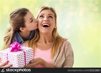 people, holidays and family concept - happy girl giving birthday present to mother over lights background. girl giving birthday present to mother over lights