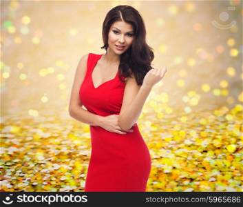 people, holidays and fashion concept - beautiful sexy woman in red dress over golden glitter or lights background