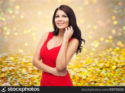 people, holidays and fashion concept - beautiful sexy woman in red dress over golden glitter or holidays lights background