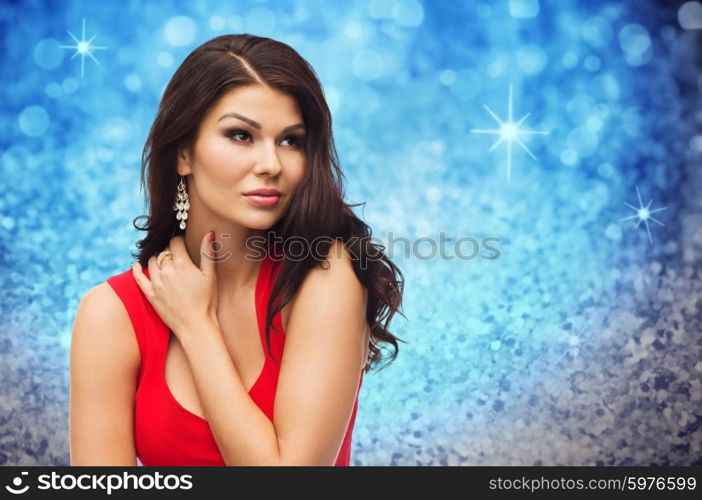 people, holidays and fashion concept - beautiful sexy woman in red dress over blue glitter or holidays lights background