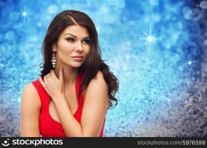 people, holidays and fashion concept - beautiful sexy woman in red dress over blue glitter or holidays lights background