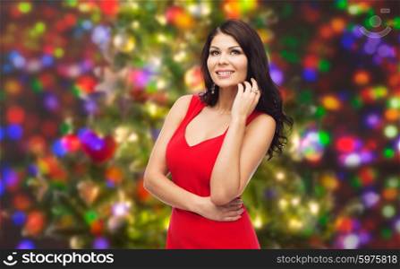 people, holidays and fashion concept - beautiful sexy woman in red dress over christmas lights background