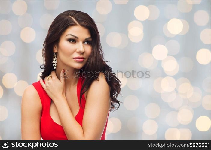 people, holidays and fashion concept - beautiful sexy woman in red dress over holidays lights background