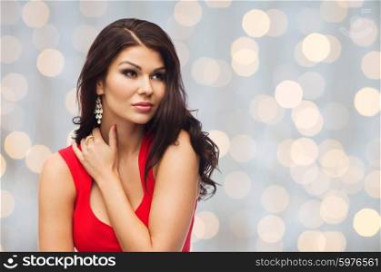 people, holidays and fashion concept - beautiful sexy woman in red dress over holidays lights background