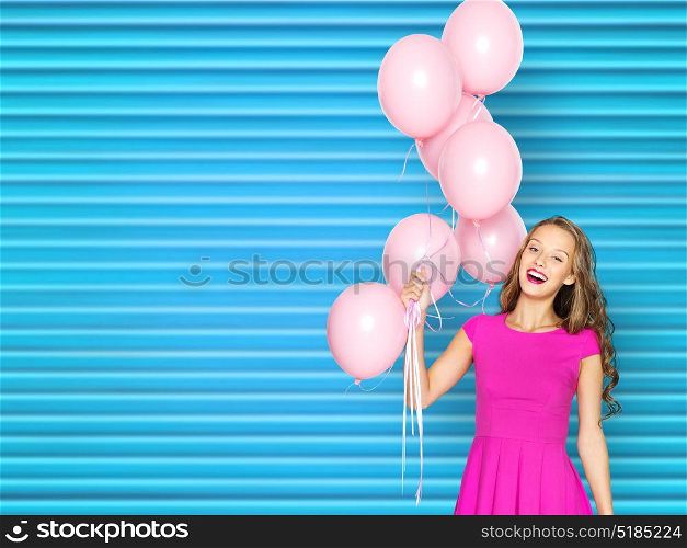 people, holidays and fashion concept - happy young woman or teen girl in pink dress with helium air balloons over blue ribbed background. happy young woman or teen girl in pink dress