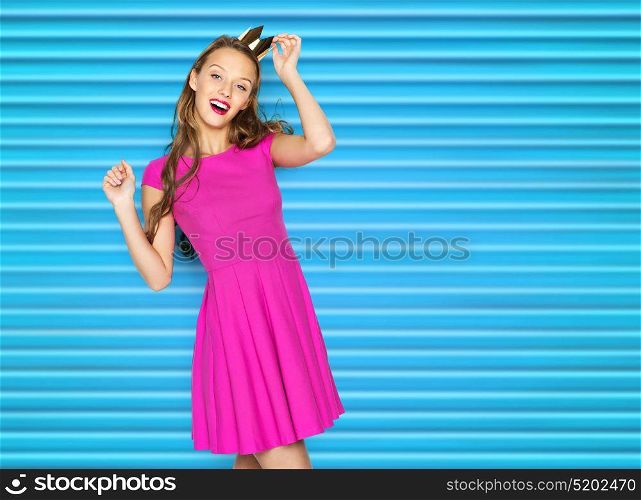 people, holidays and fashion concept - happy young woman or teen girl in pink dress and princess crown over blue ribbed background. happy young woman or teen girl in pink dress