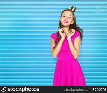 people, holidays and fashion concept - happy young woman or teen girl in pink dress and princess crown over blue ribbed background. happy young woman or teen girl in pink dress