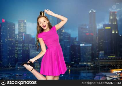 people, holidays and fashion concept - happy young woman or teen girl in pink dress and princess crown over night singapore city background