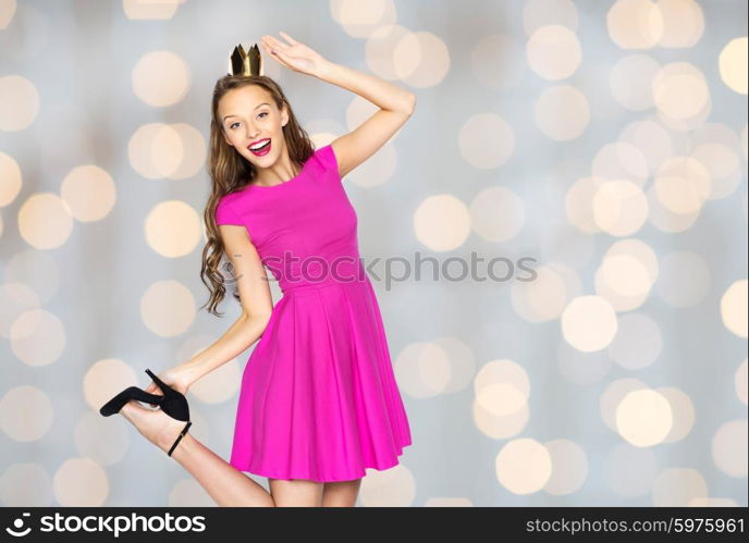 people, holidays and fashion concept - happy young woman or teen girl in pink dress and princess crown over lights background