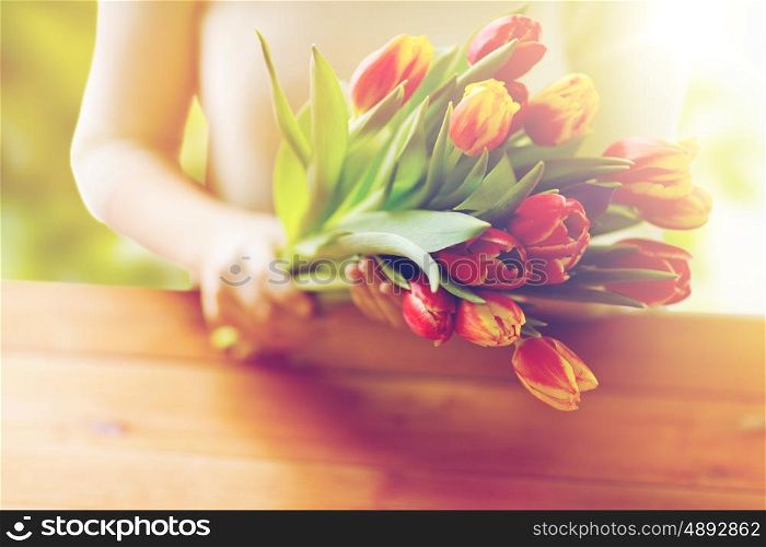 people, holidays and gardening concept - close up of woman holding tulip flowers