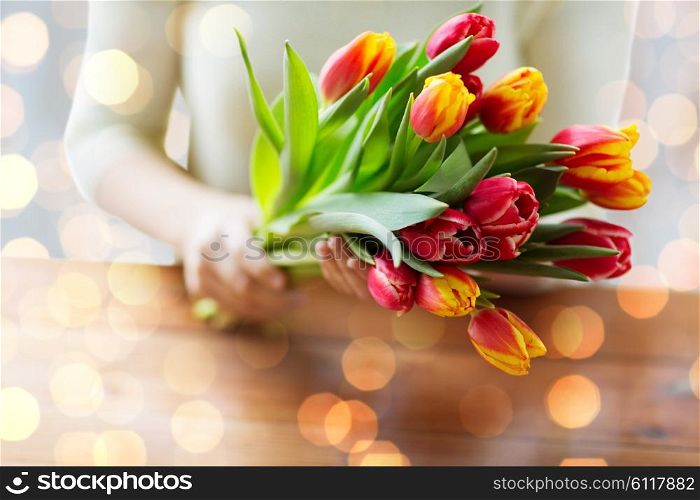 people, holidays and gardening concept - close up of woman holding tulip flowers