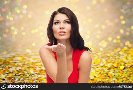 people, holidays and gesture concept - beautiful sexy woman in red dress sending blow kiss over golden glitter or holidays lights background