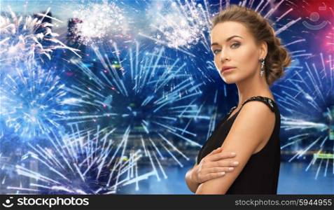 people, holidays and glamour concept - beautiful woman wearing earrings over firework at night city background