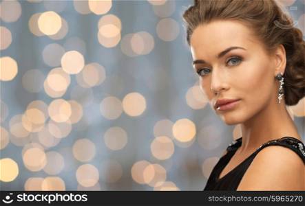 people, holidays and glamour concept - beautiful woman wearing earrings over lights background