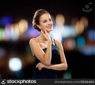 people, holidays and glamour concept - smiling woman in evening dress over black background over night lights background