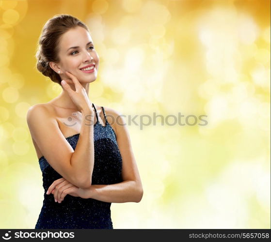 people, holidays and glamour concept - smiling woman in evening dress over black background over yellow lights background