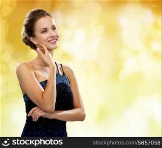 people, holidays and glamour concept - smiling woman in evening dress over black background over yellow lights background