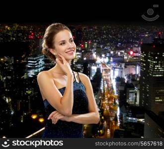 people, holidays and glamour concept - smiling woman in evening dress over black background over night city background