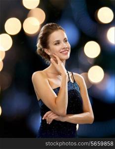 people, holidays and glamour concept - smiling woman in evening dress over black background over night lights background