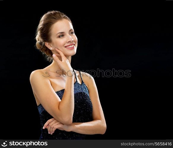 people, holidays and glamour concept - smiling woman in evening dress over black background