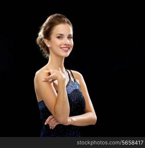people, holidays and glamour concept - smiling woman in evening dress over black background