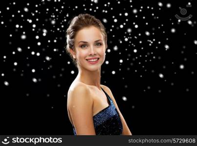 people, holidays and glamour concept - smiling woman in evening dress over black snowy background