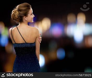 people, holidays and glamour concept - smiling woman in evening dress over night lights background