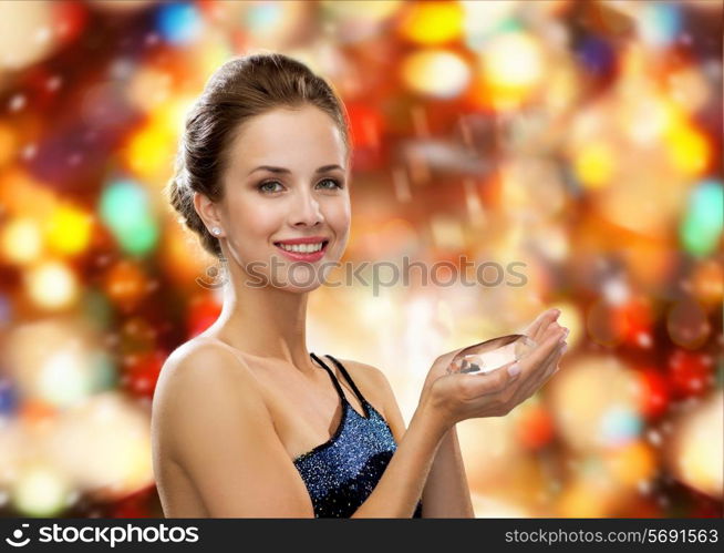 people, holidays and glamour concept - smiling woman in evening dress with diamond over red lights background