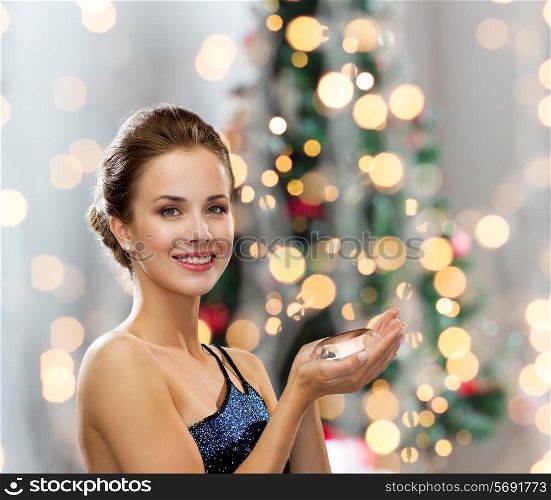 people, holidays and glamour concept - smiling woman in evening dress with diamond over christmas tree lights background