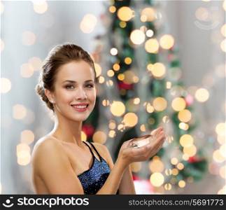 people, holidays and glamour concept - smiling woman in evening dress with diamond over christmas tree lights background