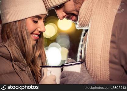 people, holidays and leisure concept - happy couple with tea cups over christmas lights. happy couple with tea cups over christmas lights