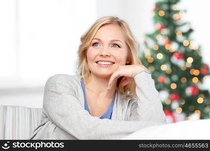 people, holidays and leisure concept - happy middle aged woman at home over christmas tree lights background