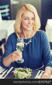 people, holidays and lifestyle concept - happy smiling woman drinking champagne at restaurant