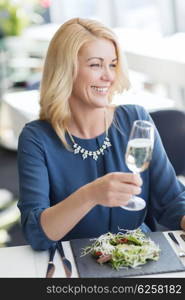 people, holidays and lifestyle concept - happy smiling woman drinking champagne at restaurant