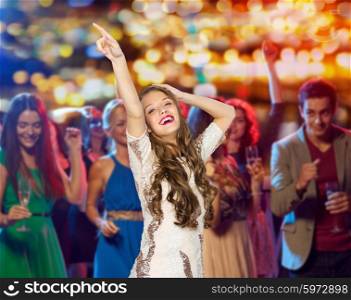 people, holidays and nightlife concept - happy young woman or teen girl in fancy dress with sequins and long wavy hair dancing at night club party over crowd and lights background