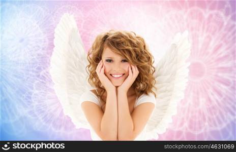 people, holidays and religious concept - happy young woman or teen girl with angel wings over rose quartz and serenity pattern background