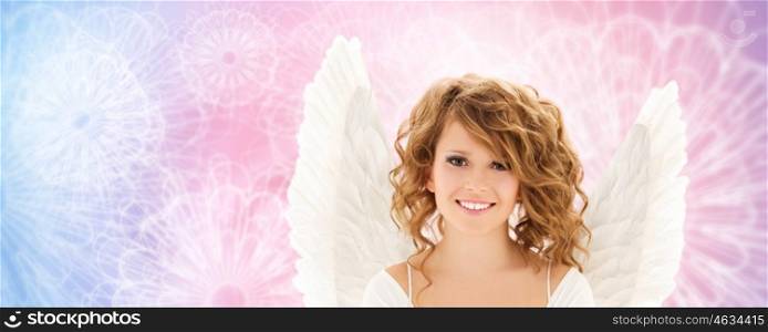 people, holidays and religious concept - happy young woman or teen girl with angel wings over rose quartz and serenity pattern background