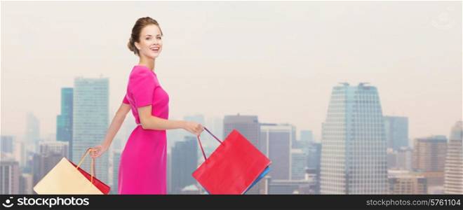 people, holidays and sale concept - young happy woman with shopping bags over city background