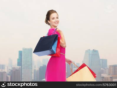 people, holidays and sale concept - young happy woman with shopping bags over city background