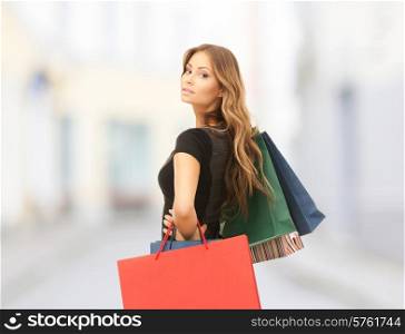 people, holidays and sale concept - young happy woman with shopping bags over city street background
