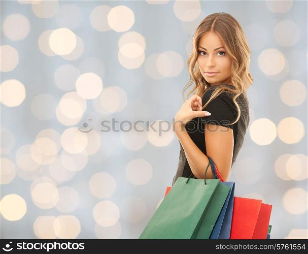people, holidays and sale concept - young happy woman with shopping bags over holidays lights background