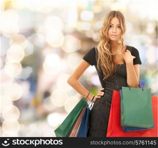 people, holidays and sale concept - young happy woman with shopping bags over lights background