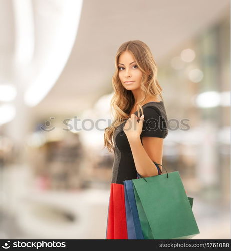 people, holidays and sale concept - young happy woman with shopping bags over mall background