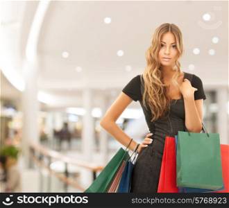 people, holidays and sale concept - young happy woman with shopping bags over mall background