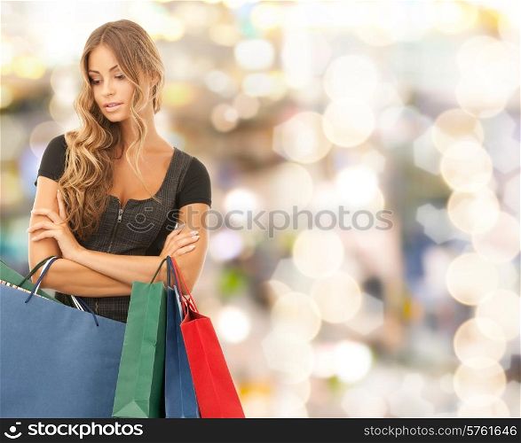 people, holidays and sale concept - young woman with shopping bags over lights background