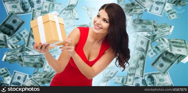 people, holidays, birthday and finances concept - beautiful sexy woman in red dress with gift box over dollar money rain on blue background