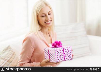 people, holidays, celebration and birthday concept - smiling young woman with gift box at home