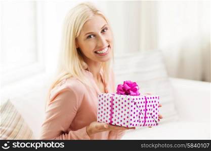 people, holidays, celebration and birthday concept - smiling young woman with gift box at home