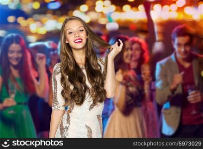 people, holidays, celebration and glamour concept - happy young woman or teen girl in fancy dress with sequins at night club party over crowd and lights background