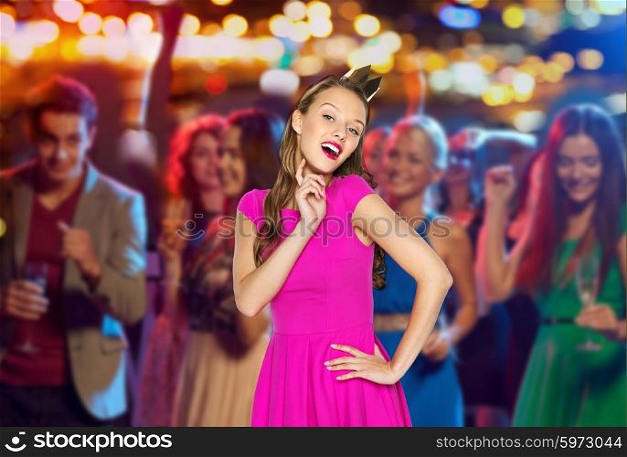 people, holidays, celebration and glamour concept - happy young woman or teen girl in pink dress and princess crown at night club party over crowd and lights background